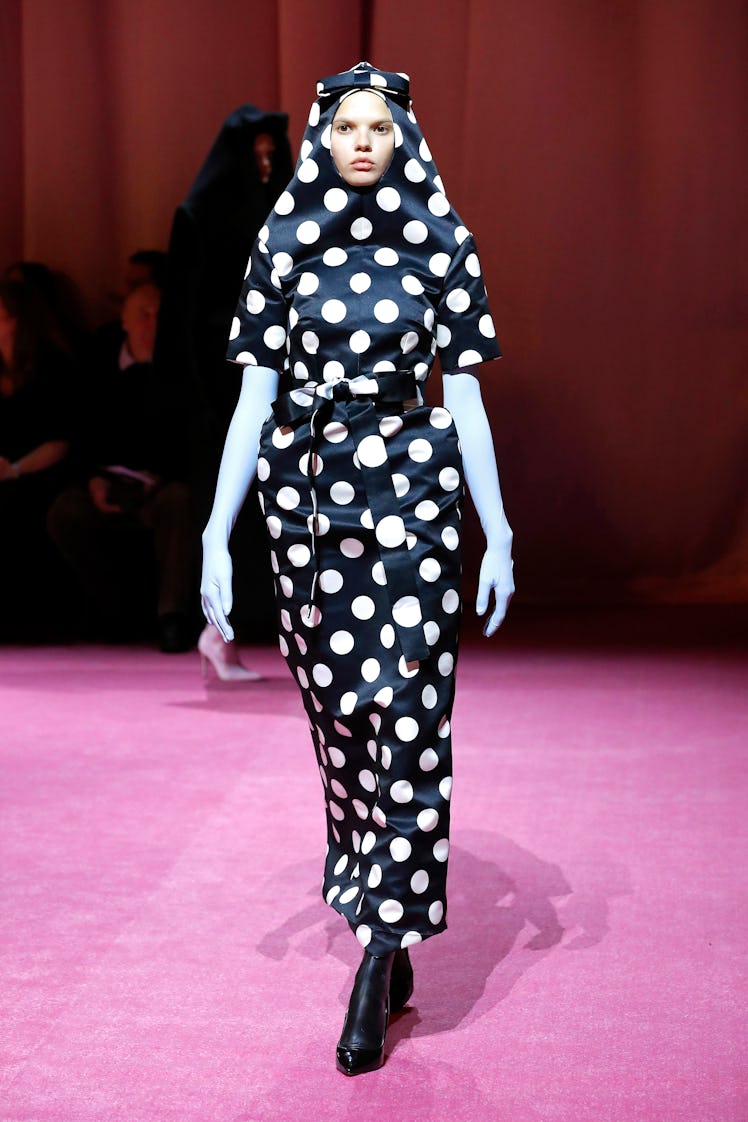 A model in a black-white polka dot dress and blue gloves by Richard Quinn at the London Fashion Week...