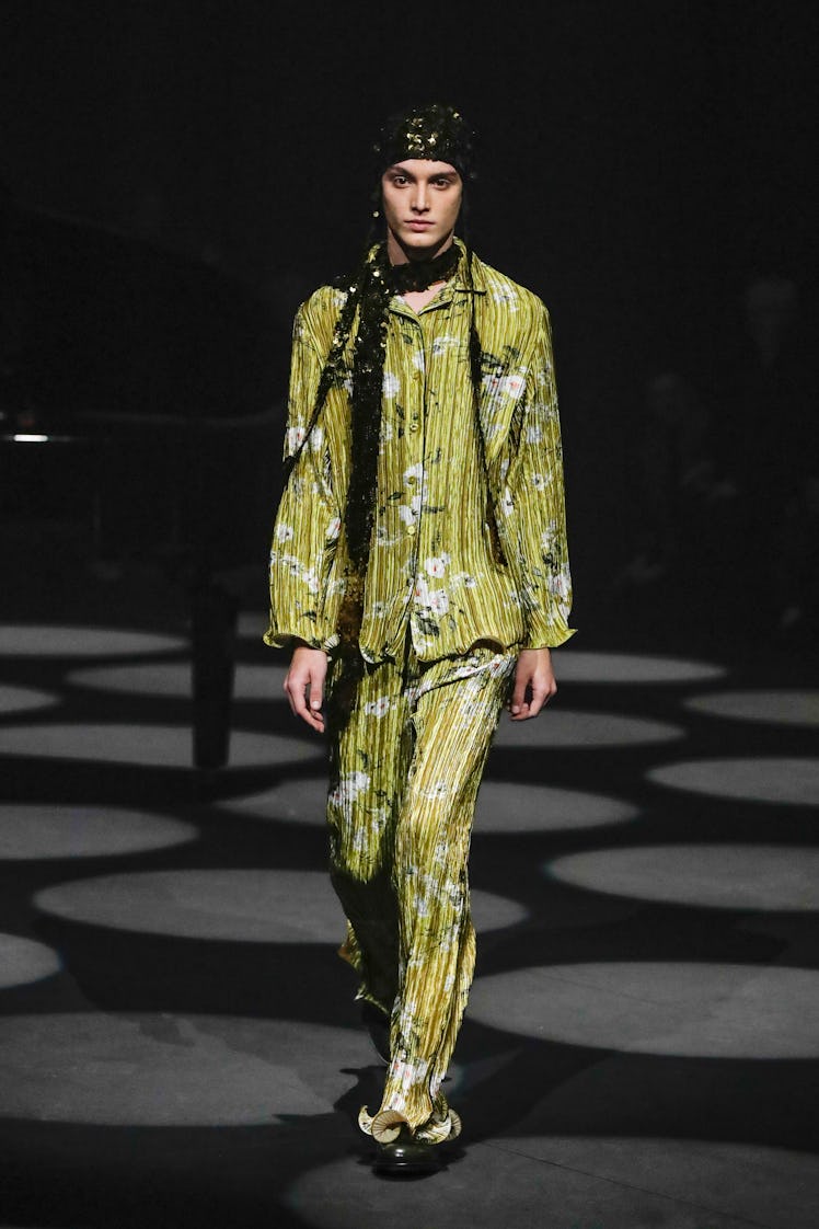 A model wearing a yellow floral shirt and pants and a black scarf by Erdem at the London Fashion Wee...