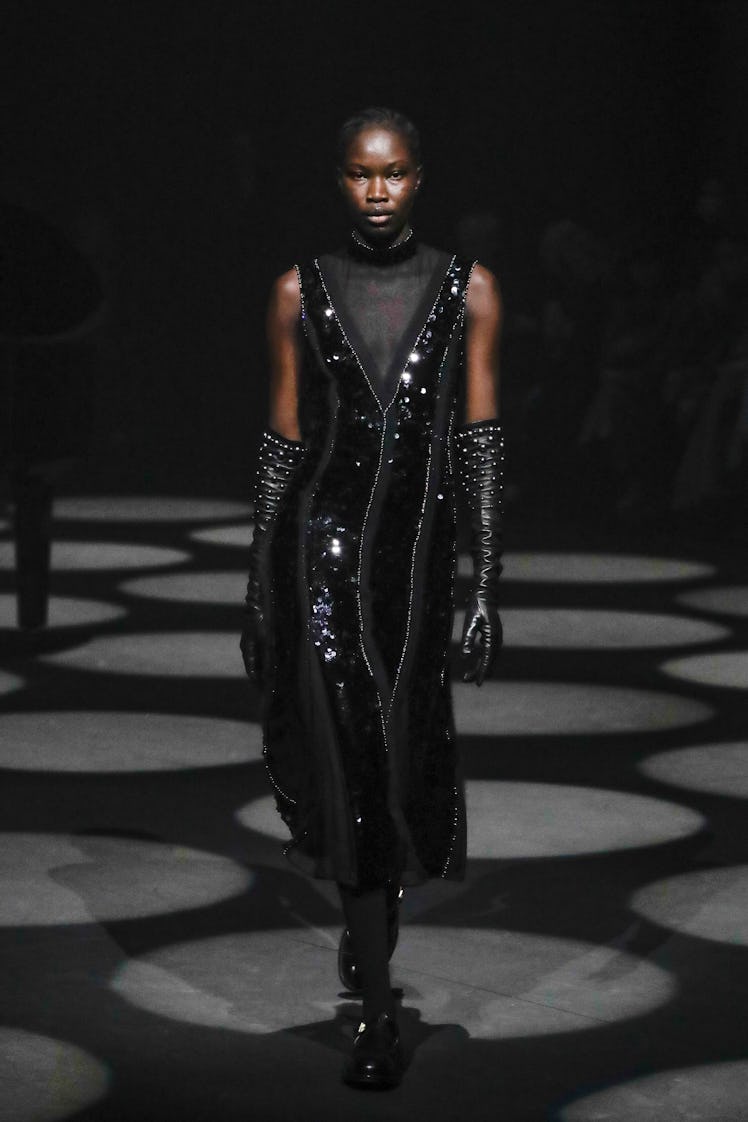 A model wearing a black tulle and sequin dress and matching gloves by Erdem at the London Fashion We...