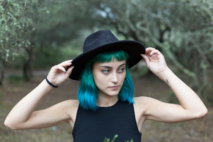 Young woman with blue hair fixing her hat, thinking about the February 28, 2022 weekly horoscope for...