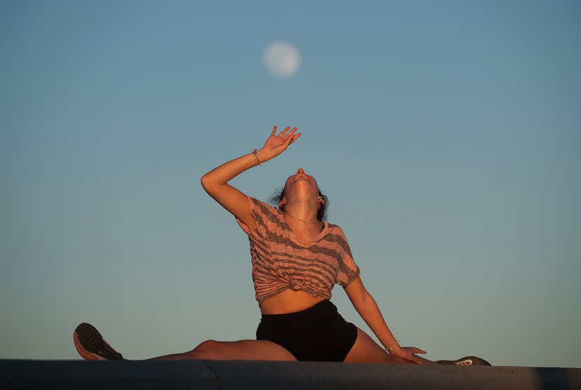 A woman does yoga under the full moon. Sun, moon, rising meaning, explained.