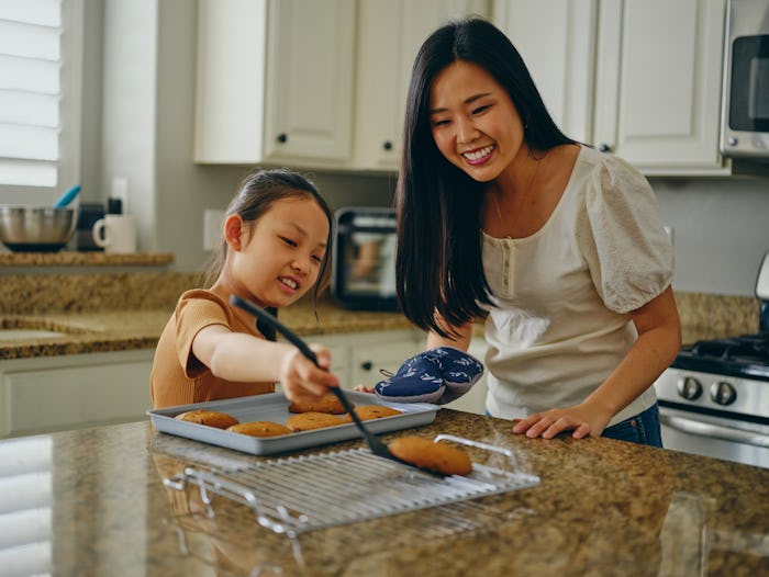 A mom and her children with freshly baked cookies in a home kitchen.