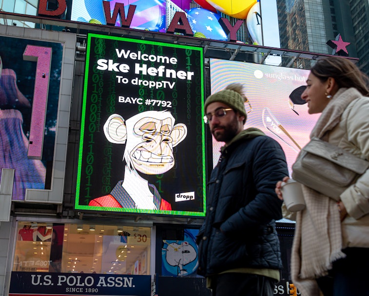NEW YORK, NEW YORK - JANUARY 25: People walk by a Bored Ape Yacht Club NFT billboard in Times Square...