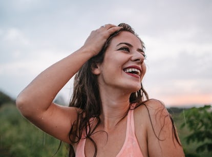 Young woman smiling in the rain, knowing the week of February 28, 2022 will be the best for her zodi...