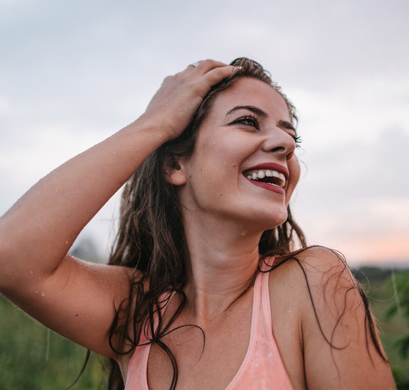 Young woman smiling in the rain, knowing the week of February 28, 2022 will be the best for her zodi...