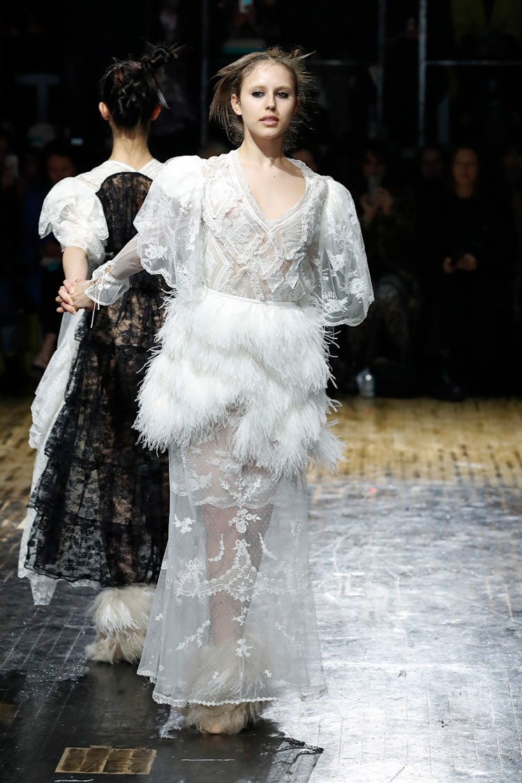 A model wearing a white lace and feather Preen by Thornton Bregazzi at the London Fashion Week Fall ...