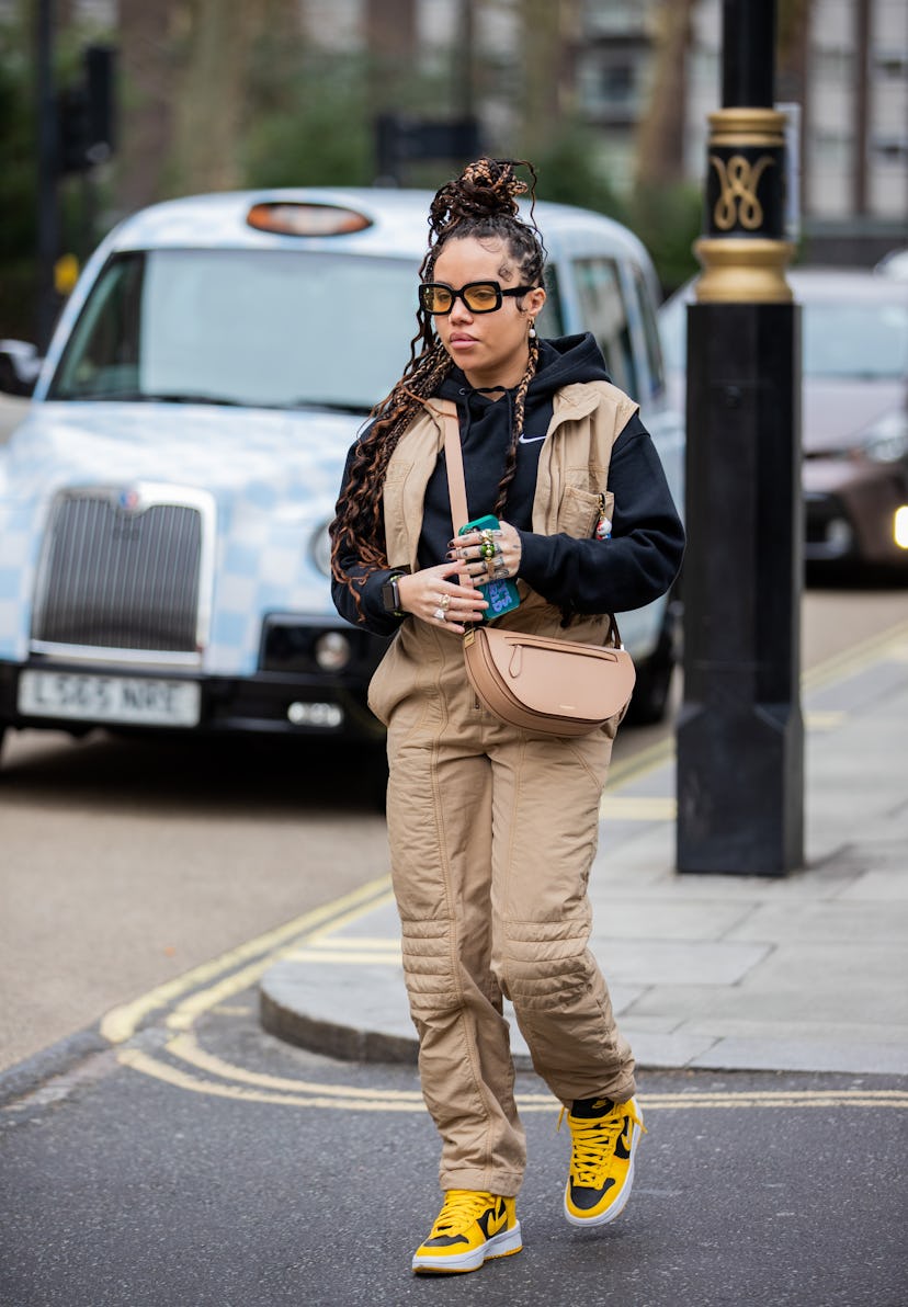 LONDON, ENGLAND - FEBRUARY 19: A guest is seen wearing beige pants, vest, black hoody, Burberry bag ...