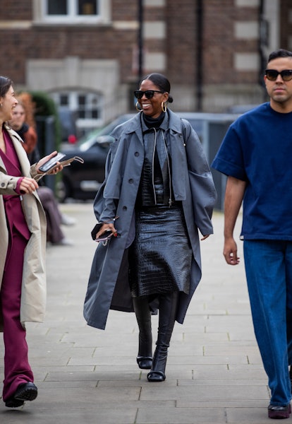 LONDON, ENGLAND - FEBRUARY 21: A guest is seen wearing grey coat, black vinyl dress, black knee high...