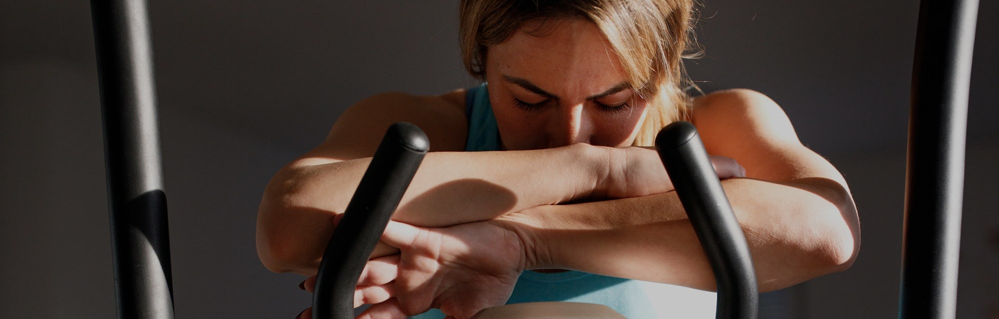 A tired woman is resting after training on a exercise bike