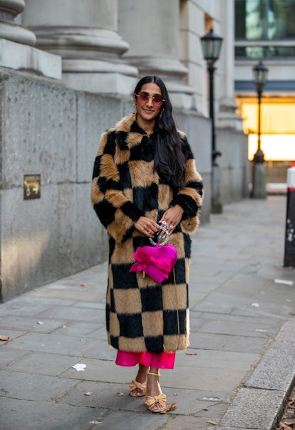 LONDON, ENGLAND - FEBRUARY 18: A guest is seen wearing beige black checkered coat, pink bag outside ...