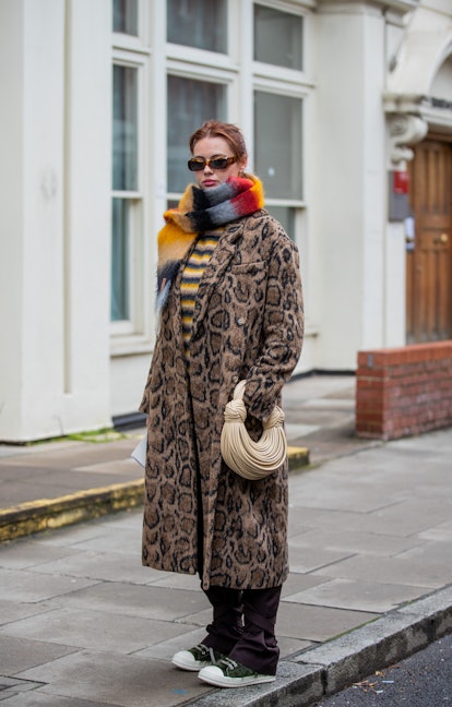 LONDON, ENGLAND - FEBRUARY 20: A guest is seen wearing Loewe scarf, beige bag, coat with animal prin...