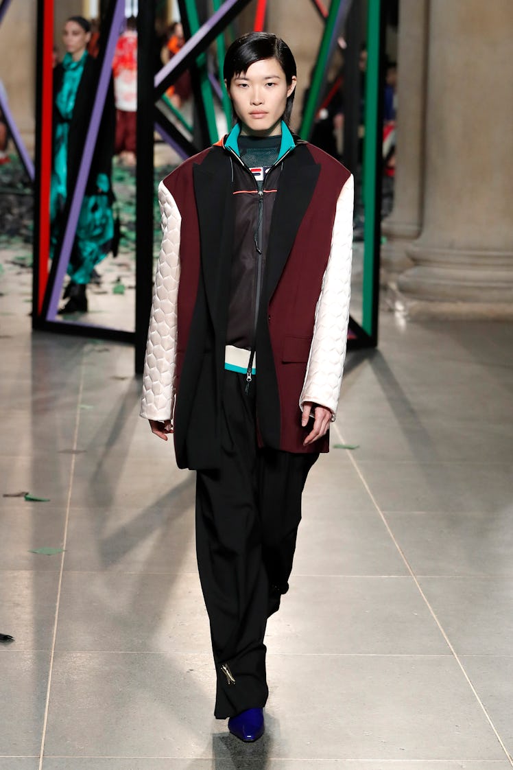 A model wearing a black hoodie, a burgundy-beige blazer and black trousers at the London Fashion Wee...