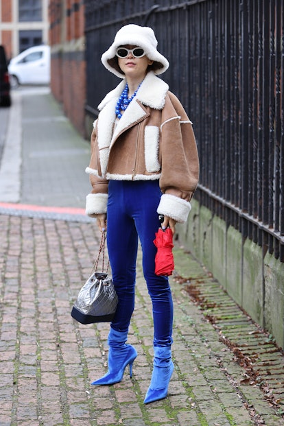 LONDON, ENGLAND - FEBRUARY 18: Guest in sheepskin coat, blue trousers and blue heels attends Bora Ak...