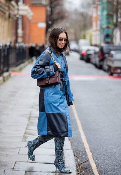 LONDON, ENGLAND - FEBRUARY 20: A guest is seen wearing checkered navy blue coat, brown bag, boots wi...