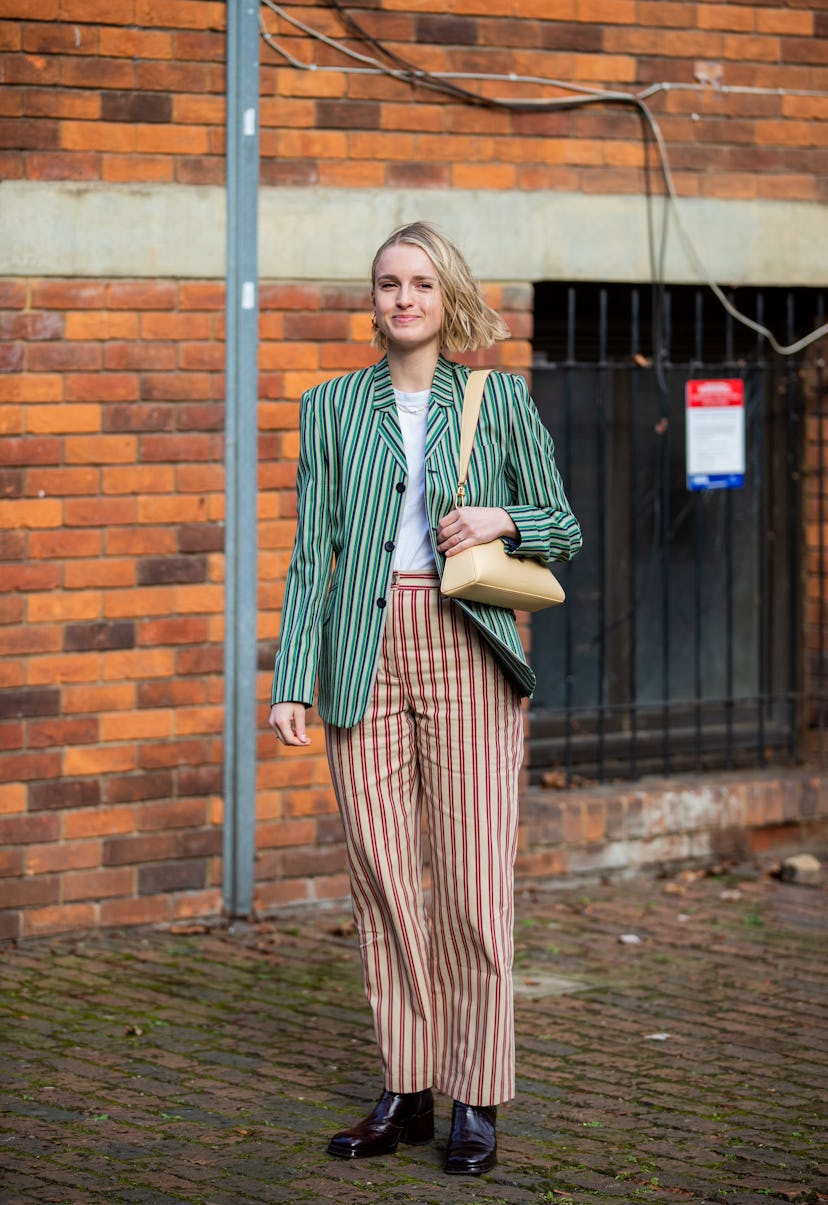 LONDON, ENGLAND - FEBRUARY 18: A guest is seen wearing striped green blazer, red striped pants, beig...