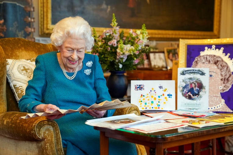 WINDSOR, ENGLAND - FEBRUARY 04: Queen Elizabeth II looks at a fan as she views a display of memorabi...