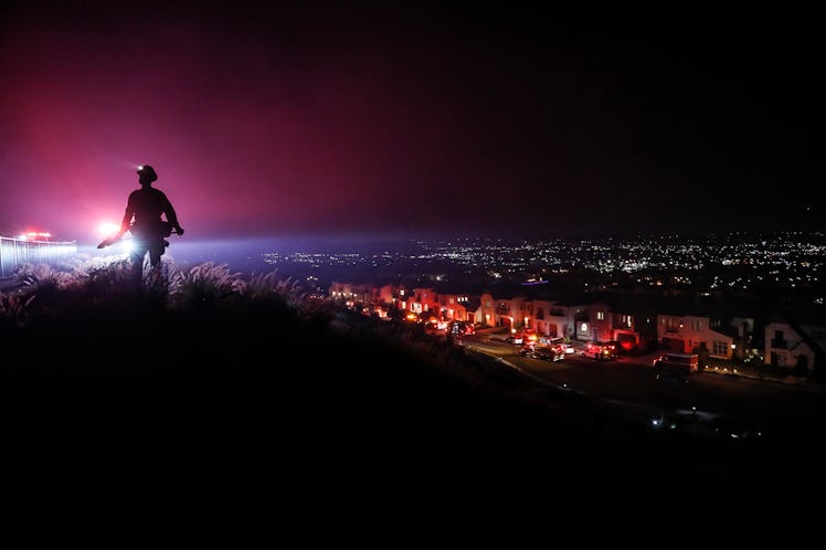 Azusa, CA, Saturday, February 12, 2022 - An LA County firefighter stands watch as dozens battle a br...