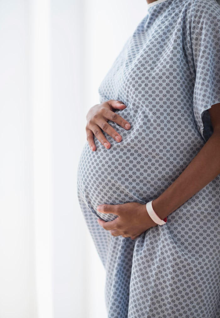A closeup of a woman holding her pregnant belly