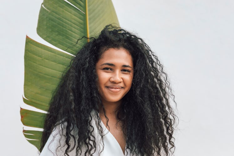 young woman poses in front of large plant as she reflects on the beginning of 2022 spring equinox