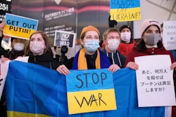 TOKYO, JAPAN - 2022/02/24: Protesters hold a Ukrainian flag with a placard reading "Stop War" during...