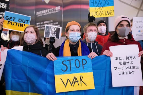 TOKYO, JAPAN - 2022/02/24: Protesters hold a Ukrainian flag with a placard reading "Stop War" during...