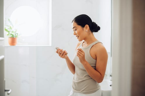 Beautiful woman smiling and holding a bottle of a beauty product.