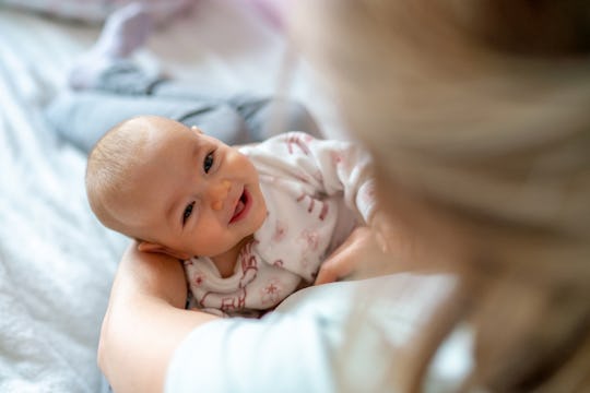 Mother carrying her smiling baby girl at home