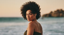 Young woman standing on the beach, knowing the March 2022 new moon in Pisces will affect her zodiac ...