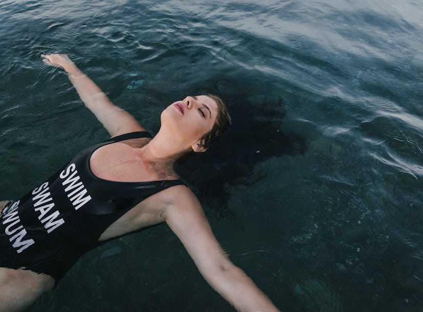 Young woman on her back enjoying in calm water, knowing her zodiac sign will be affected by the Marc...