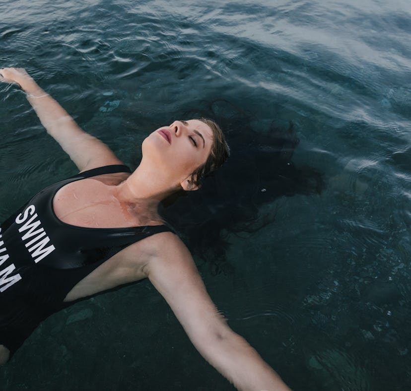 Young woman on her back enjoying in calm water, knowing her zodiac sign will be affected by the Marc...