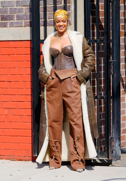 Rihanna wears a corset and paperbag pants.