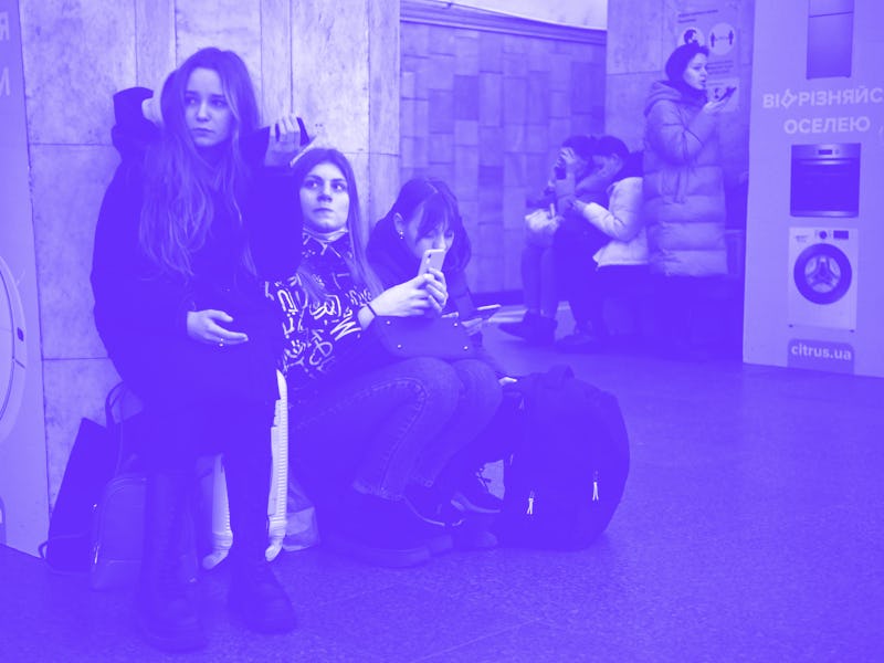Girls hold their mobile phone as they take refuge in a metro station in Kyiv in the morning of Febru...