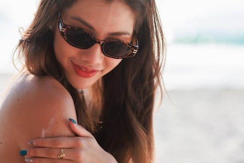 Asian woman using sunscreen cream on her shoulder.