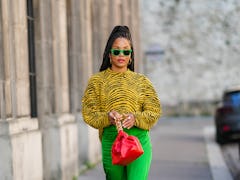 PARIS, FRANCE - JANUARY 14: Ellie Delphine wears neon green sunglasses, gold earrings, a yellow and ...