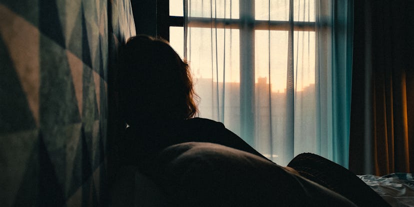 Woman looking out the window at a sunset.