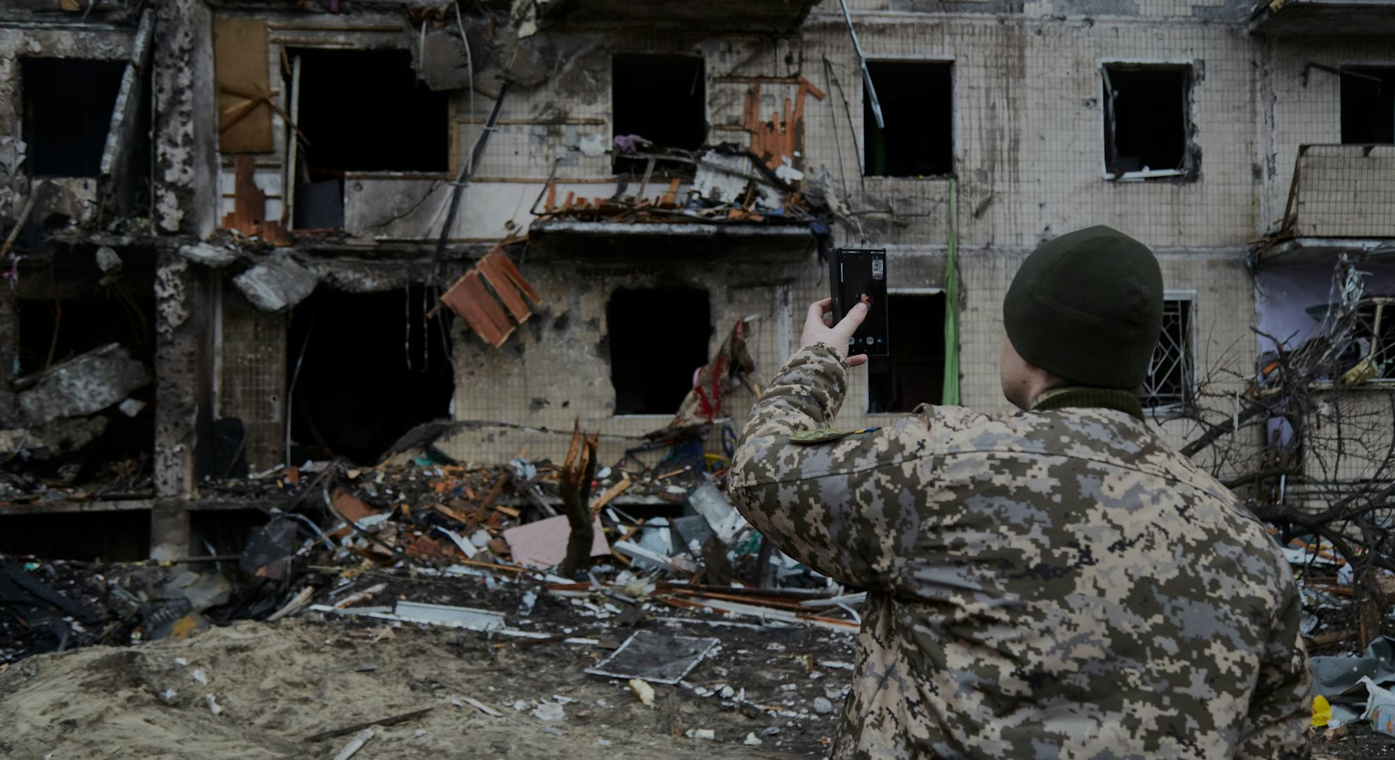 KYIV, UKRAINE - FEBRUARY 25: A Ukrainian soldier speaks on his smartphone outside a residential buil...