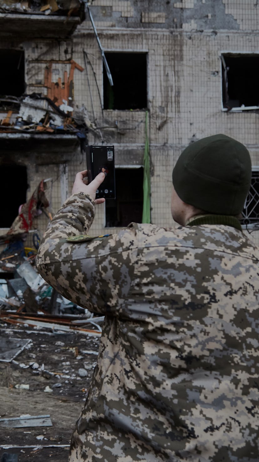 KYIV, UKRAINE - FEBRUARY 25: A Ukrainian soldier speaks on his smartphone outside a residential buil...