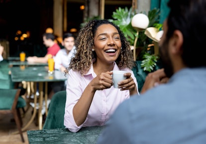 Happy African American woman smiling while having a cup of coffee on a date at a cafe