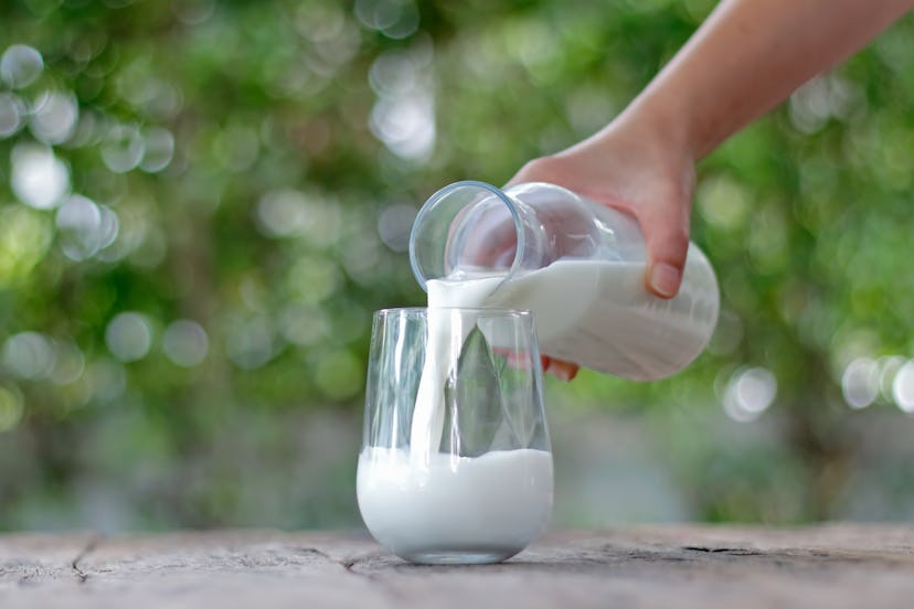Pouring milk in the glass on wooden table