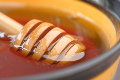 close up of fresh honey with spoon on table .