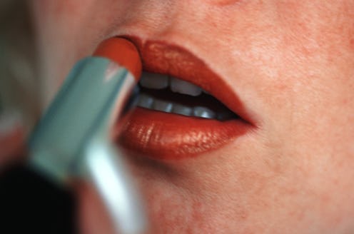woman putting on lipstick up close