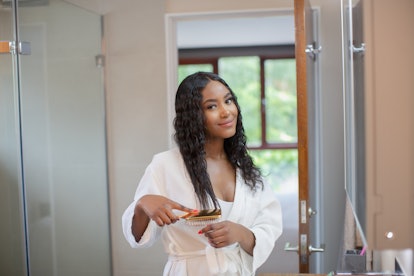 Portrait beautiful smiling young woman brushing hair in bathroom