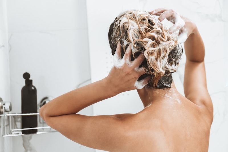 Rear View Of Female Washing Hair In Shower