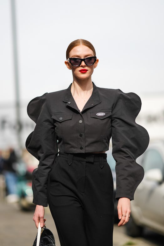 MILAN, ITALY - FEBRUARY 24: Larsen Thompson wears black sunglasses, a black shirt with puffy sleeves...
