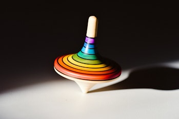 Rainbow colored wooden spinning top on white surface