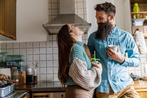 A young couple laughs in a kitchen. Here’s your daily horoscope for February 28 2022.