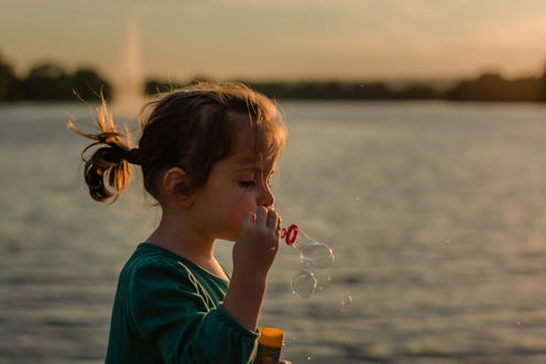 Girl blowing bubbles during sunset by lake