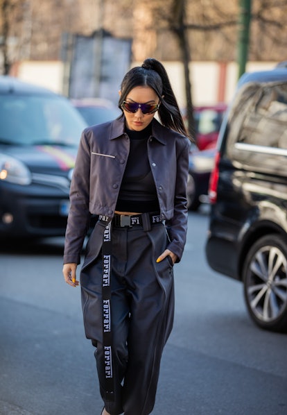 Jessica Wang seen wearing cropped jacket, navy pants, belt, cycle sunglasses outside Milan Fashion W...