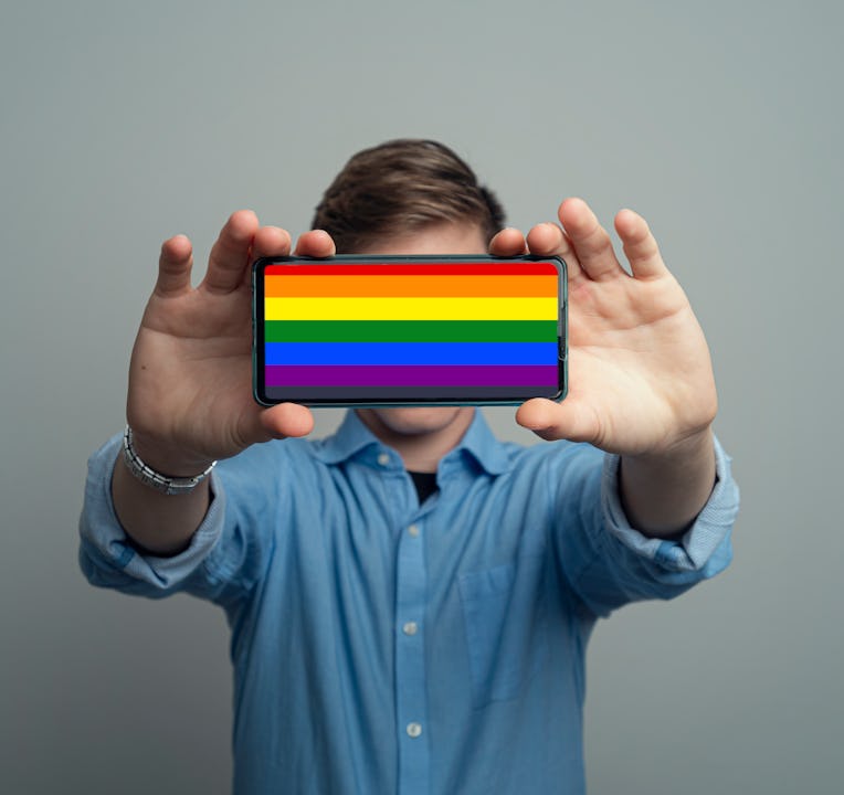 oung man Holding Smartphone With a Rainbow or Pride Flag