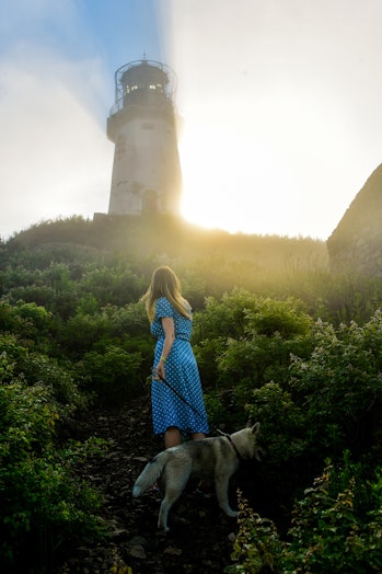PRIMORYE TERRITORY, RUSSIA - JULY 22, 2020: A woman with a dog walks by the Rudny Lighthouse on Cape...
